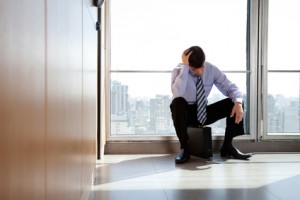 Upset Business man Sitting on Briefcase